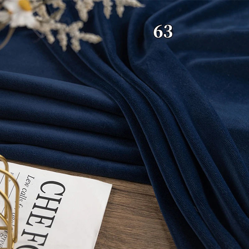 A folded piece of Longon Craft Stretch Minky Fabric by the yard in dark blue lies on a wooden surface, beside a magazine and dried flowers. The number 63 is printed on this four-way stretch cuddle minky material for DIY projects.