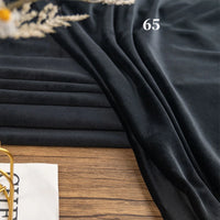 Longon Craft Stretch Minky Fabric by the yard is shown in black, draped on wood with “65” in white text. Plush and soft, this multicolor four-way stretch cuddle fabric is perfect for DIY clothing, pillows, plushies, and dolls. Dried flowers are visible nearby.