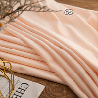 A piece of Longon Craft Stretch Minky Fabric By The Yard in multicolor four-way stretch is neatly folded on a wooden surface with "68" above it and part of a magazine nearby—ideal for DIY clothing, plushies, dolls, or cozy blankets.