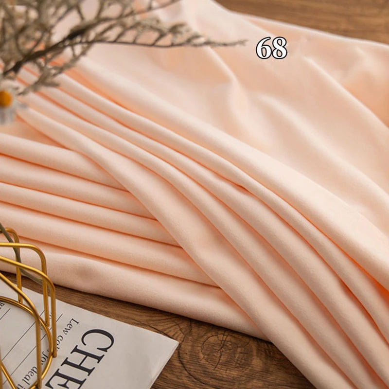 A piece of Longon Craft Stretch Minky Fabric By The Yard in multicolor four-way stretch is neatly folded on a wooden surface with "68" above it and part of a magazine nearby—ideal for DIY clothing, plushies, dolls, or cozy blankets.