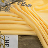 Longon Craft Stretch Minky Fabric By The Yard in yellow, draped on wood with a magazine at the corner and "96" above. Soft four-way stretch cuddle minky—ideal for cozy baby blankets, DIY clothing, pillows, plushies, and dolls.