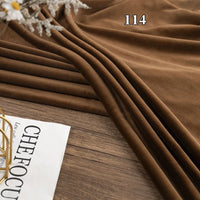Longon Craft's Stretch Minky Fabric By The Yard in brown is displayed on a wooden surface beside a white paper with black text. This multicolor four-way stretch cuddle minky material is great for DIY clothing, pillows, plushies, and dolls.