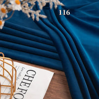 A piece of Longon Craft Stretch Minky Fabric By The Yard in multicolor, labeled "116," sits on a wooden surface beside a magazine, gold wire basket, and dried flowers—perfect for DIY clothing, pillows, plushies, or dolls.