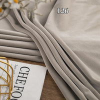 A close-up of Longon Craft's Stretch Minky Fabric (126), a beige, plush, four-way stretch material perfect for DIY baby blankets, clothing, pillows, and plushies; part of a magazine and wire appear in the lower left corner.