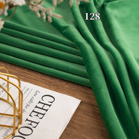Longon Craft Stretch Minky Fabric By The Yard in green is draped on wood near a magazine, with the number 128 shown on the plush multicolor four-way stretch cuddle material for DIY clothing, pillows, plushies, and dolls.