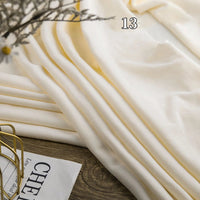 A piece of Longon Craft Stretch Minky Fabric By The Yard, a multicolor four-way stretch cuddle material for DIY clothing, pillows, and plushies, is draped on wood next to a magazine and wire basket with the number 13 in view.