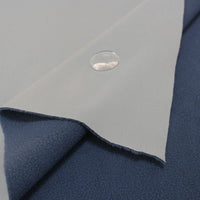 A close-up of Longon Craft Waterproof Polar Fleece Fabric By The Yard shows its water-resistant, light gray surface with a water droplet, layered over dark blue fleece. This 4 way stretch polyester fabric is ideal for sewing and crafts.