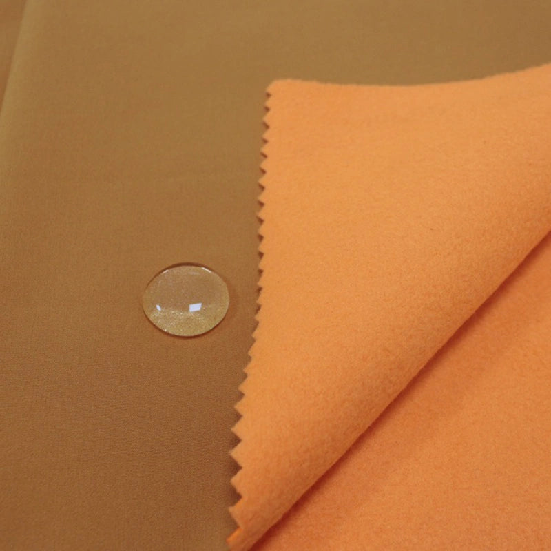 A close-up of Longon Craft Waterproof Polar Fleece Fabric By The Yard shows water beading on the smooth surface, demonstrating the 4-way stretch polyester material’s water-resistant properties.