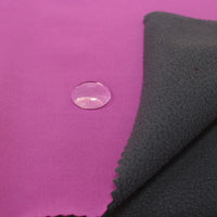 A water droplet on Longon Craft's Waterproof Polar Fleece Fabric by the Yard highlights its water-resistant, 4-way stretch polyester material with a bright pink surface and gray fleece-like underside.
