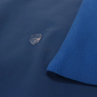 A close-up of Longon Craft Waterproof Polar Fleece Fabric By The Yard, showing water beading on the blue 4-way stretch polyester fleece and a folded corner revealing its soft inner layer, ideal for sewing and crafts.