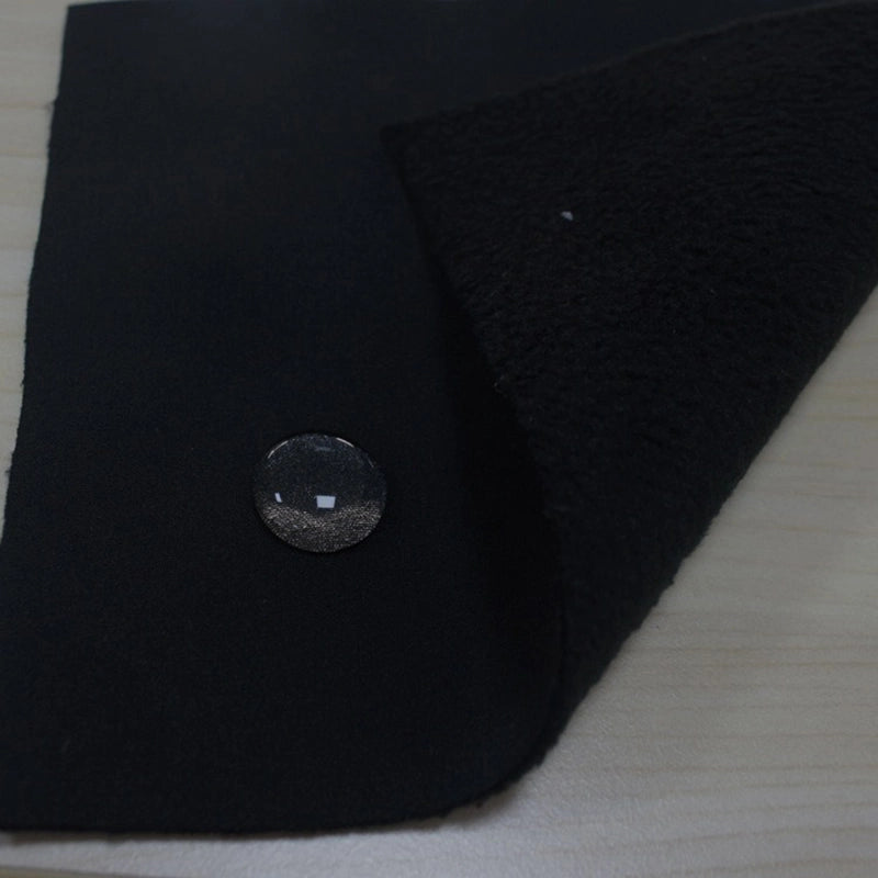 A piece of Longon Craft Waterproof Polar Fleece Fabric By The Yard is shown with water beading on its surface, highlighting its water resistance. The 4-way stretch polyester fleece is partially folded to display its textured underside on a wooden background.