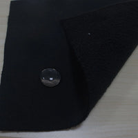 A piece of Longon Craft Waterproof Polar Fleece Fabric By The Yard is shown with water beading on its surface, highlighting its water resistance. The 4-way stretch polyester fleece is partially folded to display its textured underside on a wooden background.